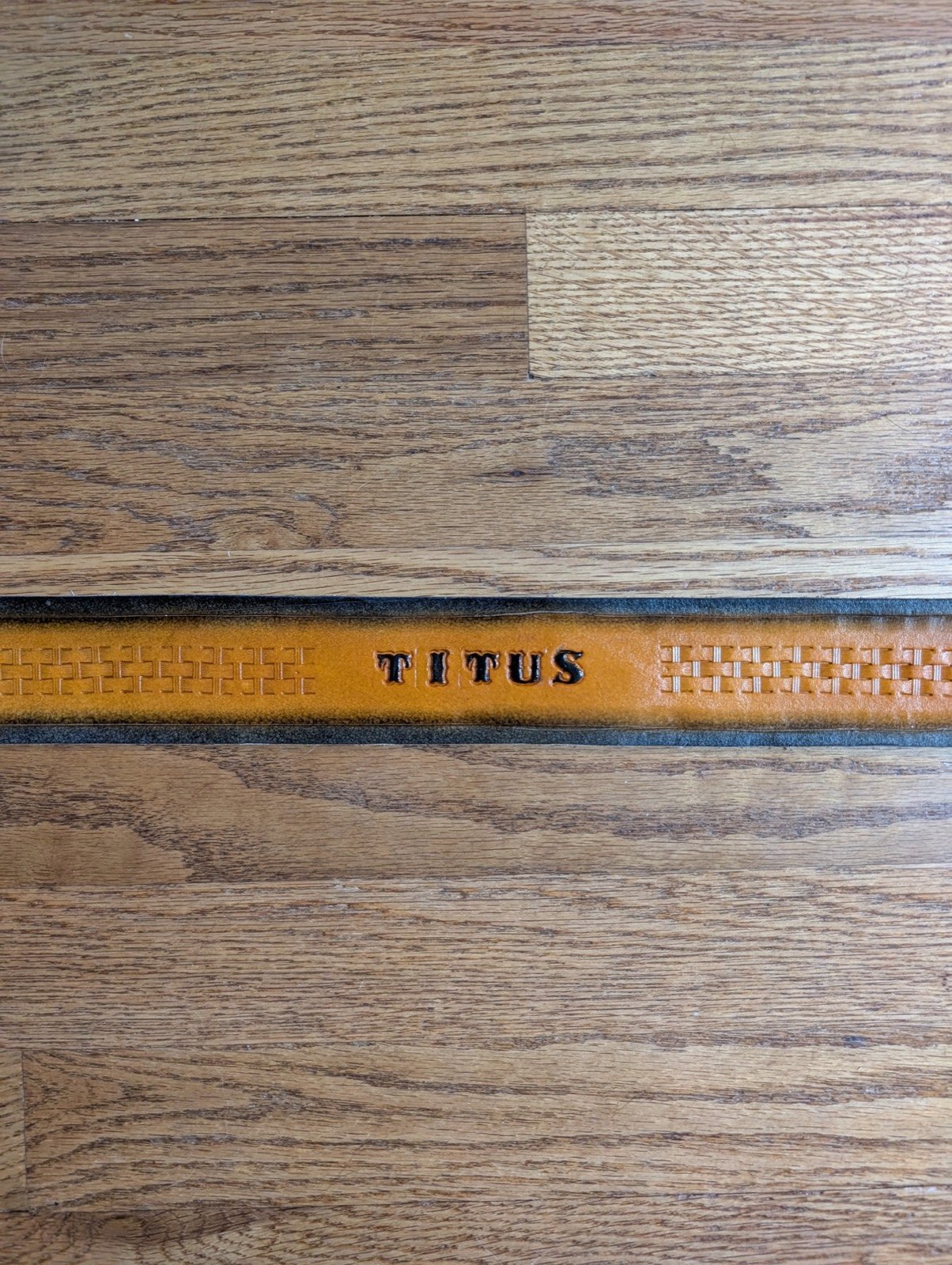 A name, TITUS, hand-tooled into a leather belt strap