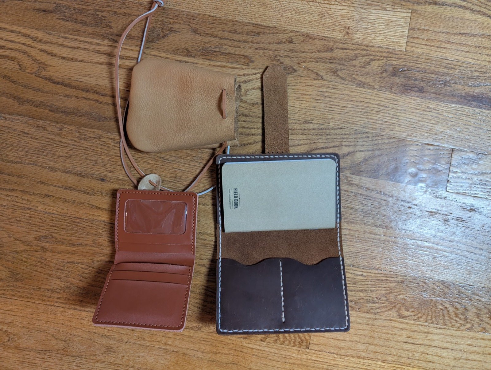 Drawstring pouch, trifold wallet, and leather notebook cover laid out together